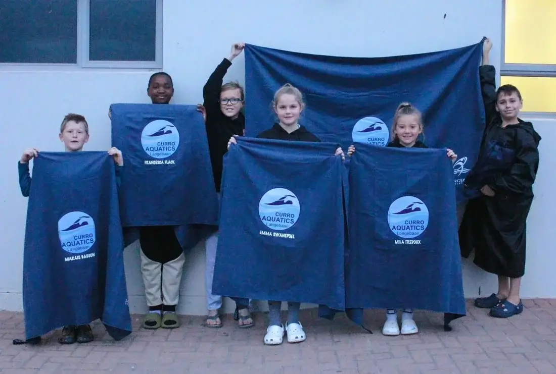 Swimming club members holding blue towels with matching club logos
